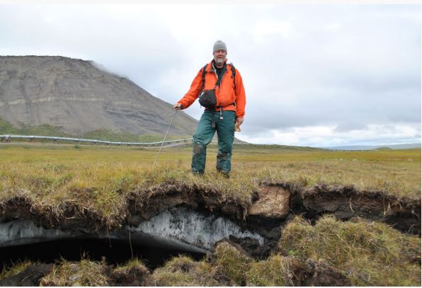 NSIDC research scientist Kevin Schaefer stands above melting ground ice in front of the Alaska pipeline on the North Slope. 